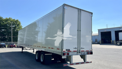 Fruehauf van trailer with white exterior, dual rear doors, and a light gray underslung chassis. Side view shows a large graphic of a flying crane on the midsection.
