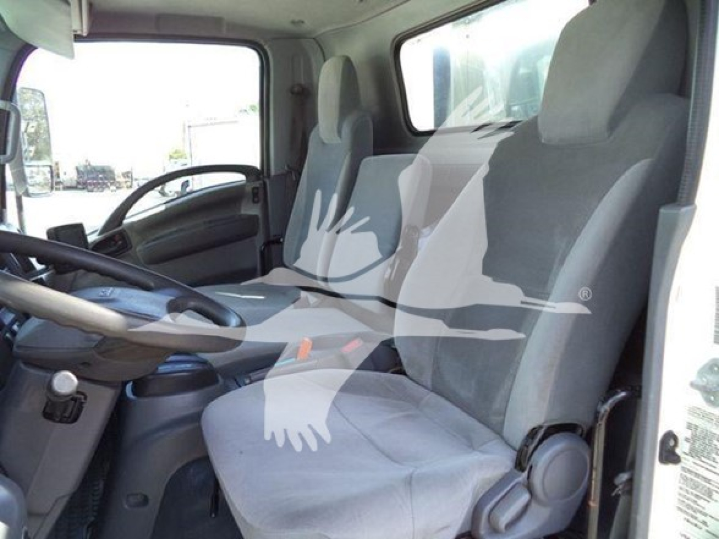 Isuzu NPR HD cab interior view showing front seats, steering wheel, and dashboard from the driver’s side.
