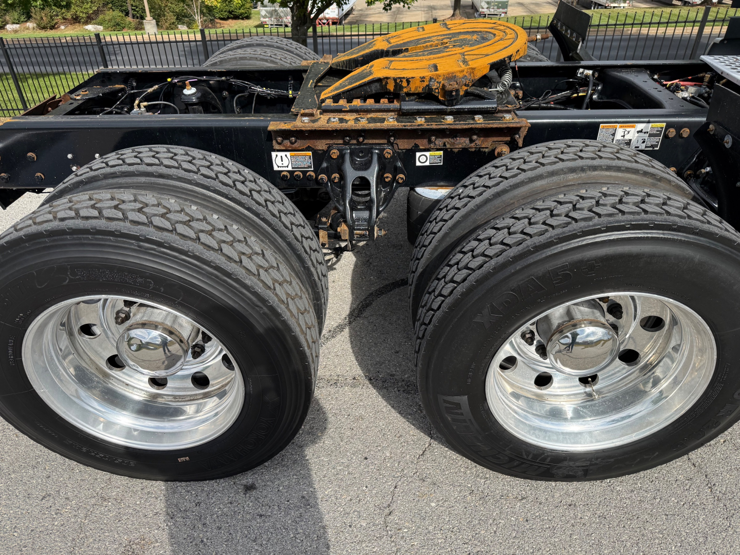 Kenworth T680 chassis with dual rear axles and chrome wheels showing the fifth wheel and frame, tires, and suspension components.