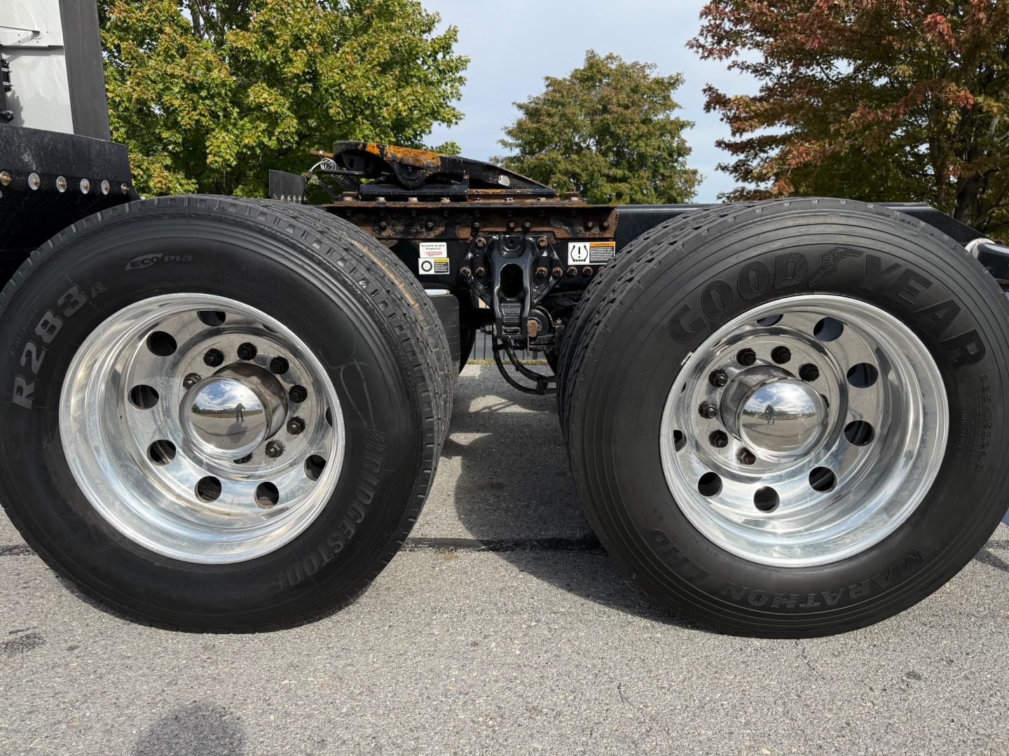 Kenworth T680 wheel configuration showing dual rear axles and Goodyear tires with chrome hubcaps; view focuses on rear chassis and drivetrain area.