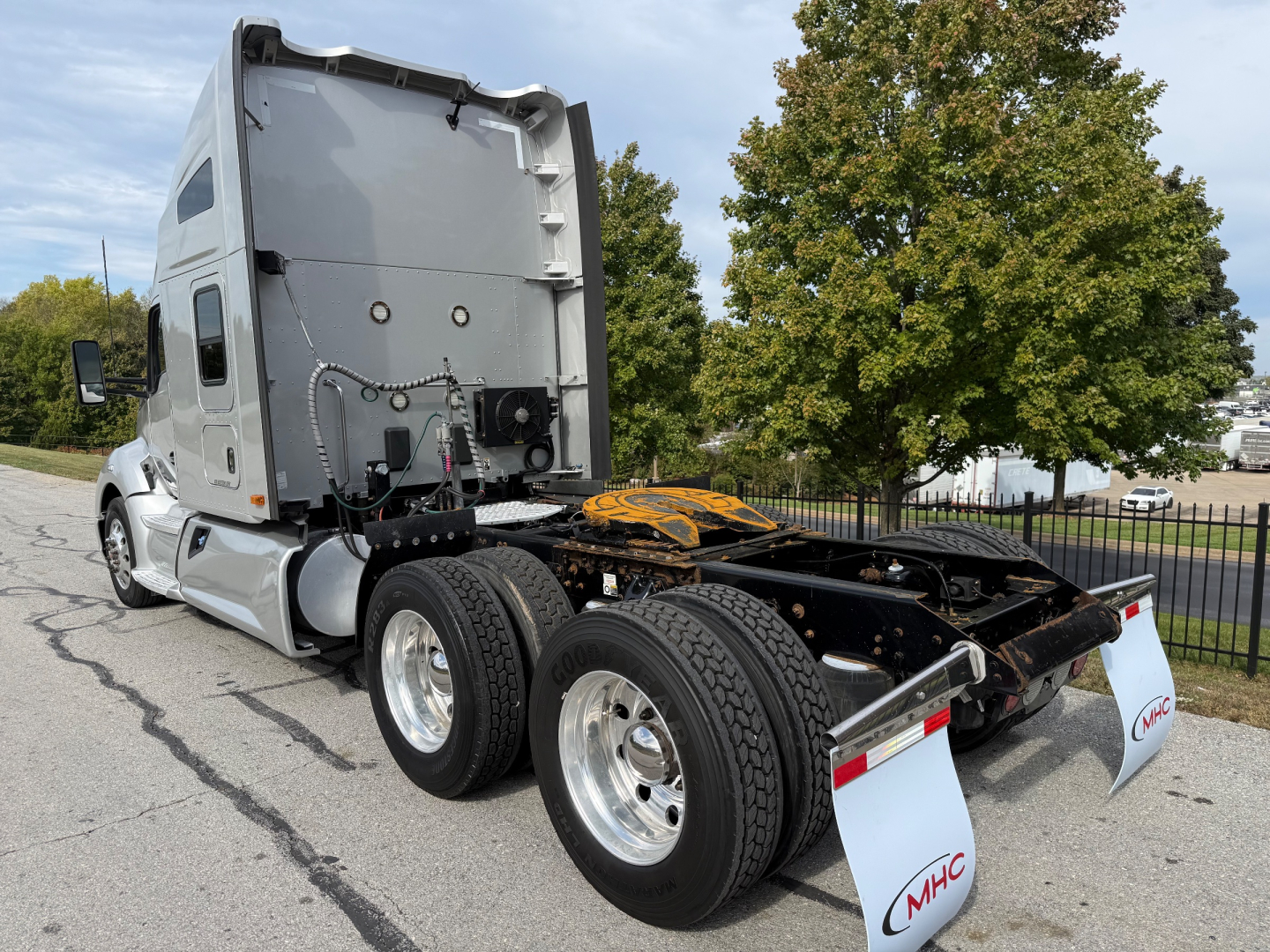Kenworth T680 tractor rear view showing fifth wheel and dual rear axles with MHC mud flaps. Side panel text not legible.