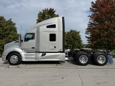 Kenworth T680 sleeper cab tractor showing side profile with silver paint and fifth wheel, two rear axles, and front wheels.