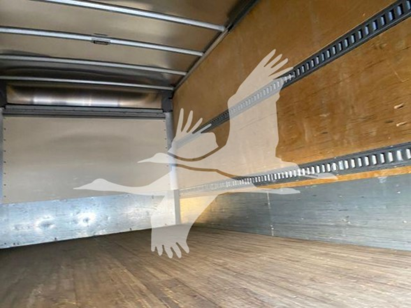 Interior cargo area of a 2019 Isuzu NQR box truck viewed from rear, showing wooden side walls and metal tie rails.