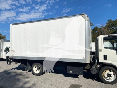 Isuzu NQR box truck side view showing cargo box and front cab with white exterior and blue sky.