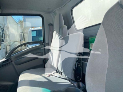Isuzu NQR cab interior showing driver seat and passenger bench seating with gray fabric, dashboard, and steering wheel.