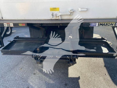Isuzu NQR truck undercarriage showing dump bed mechanism and flatbed hitch with hydraulic components.