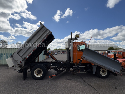 Mack GU712 dump trucks in service position showing dual bed dumps and orange cab.