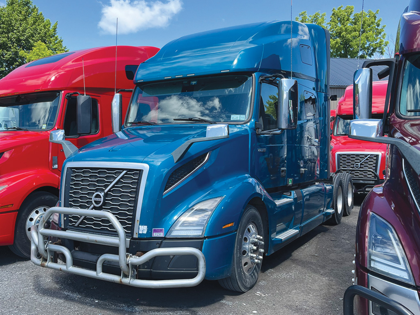 Volvo VNL 760 sleeper cab truck in blue with front bull bar and chrome grille in a lot of colorful trucks.