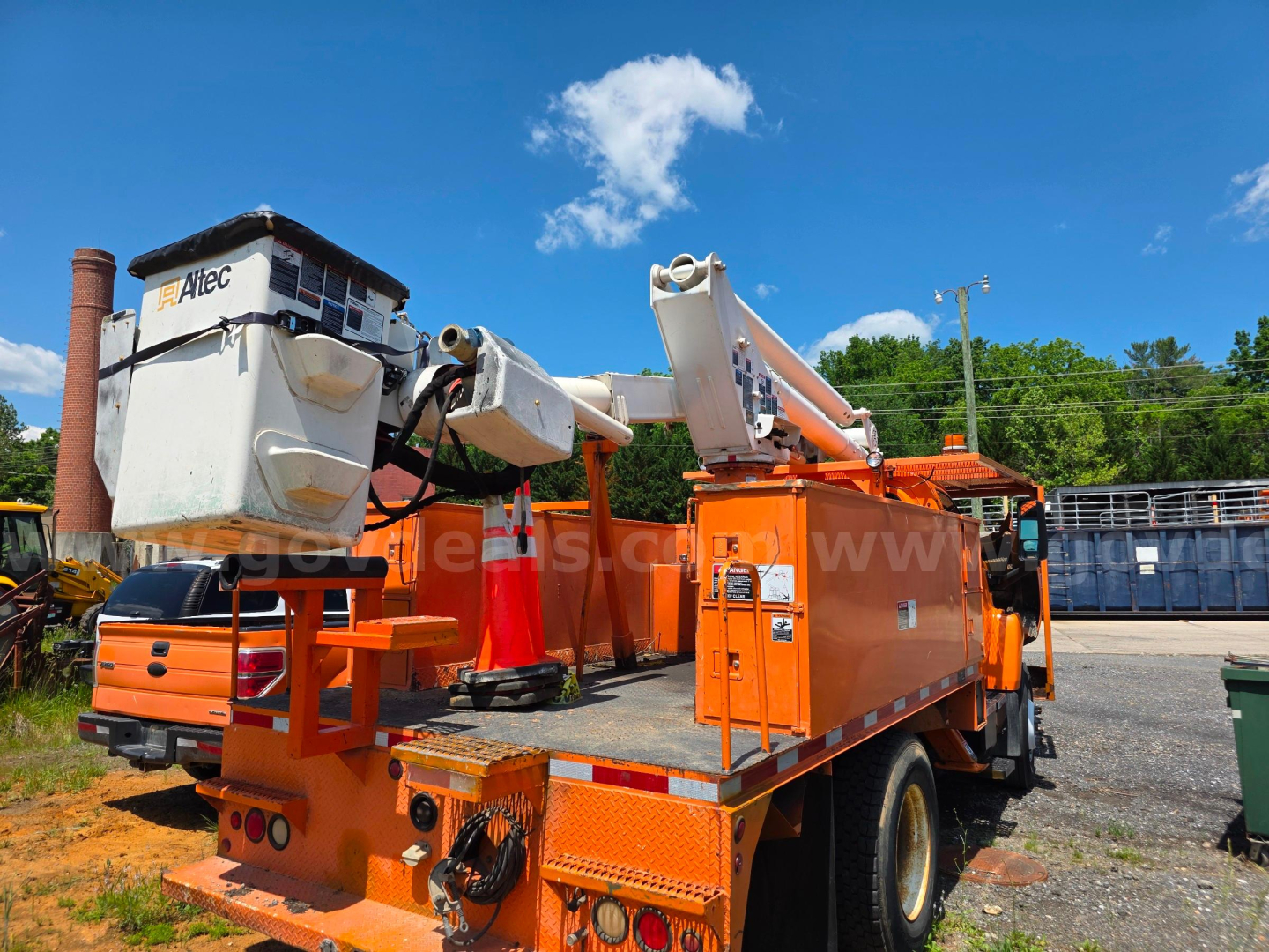 Altec TA45M bucket truck on bed with hydraulic boom arms and bucket, orange chassis, with cab visible in background.