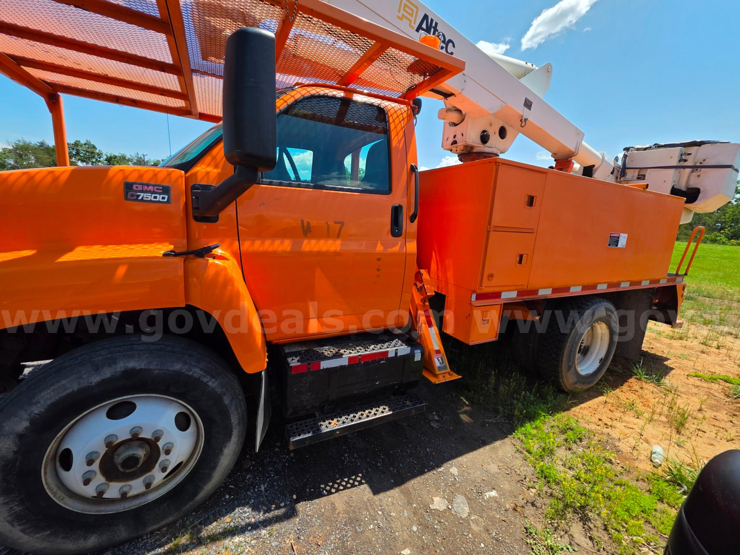 Altec TA45M bucket truck front cab and utility bed with elevated boom, orange color, GMC chassis badge, side steps, and bucket attachment.
