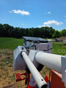 Altec TA45M boom truck arm telescoping cylinder and control cab visible in field.