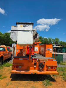 Altec TA45M bucket truck chassis rear view with orange bed and bucket crane, service markings, blue sky.