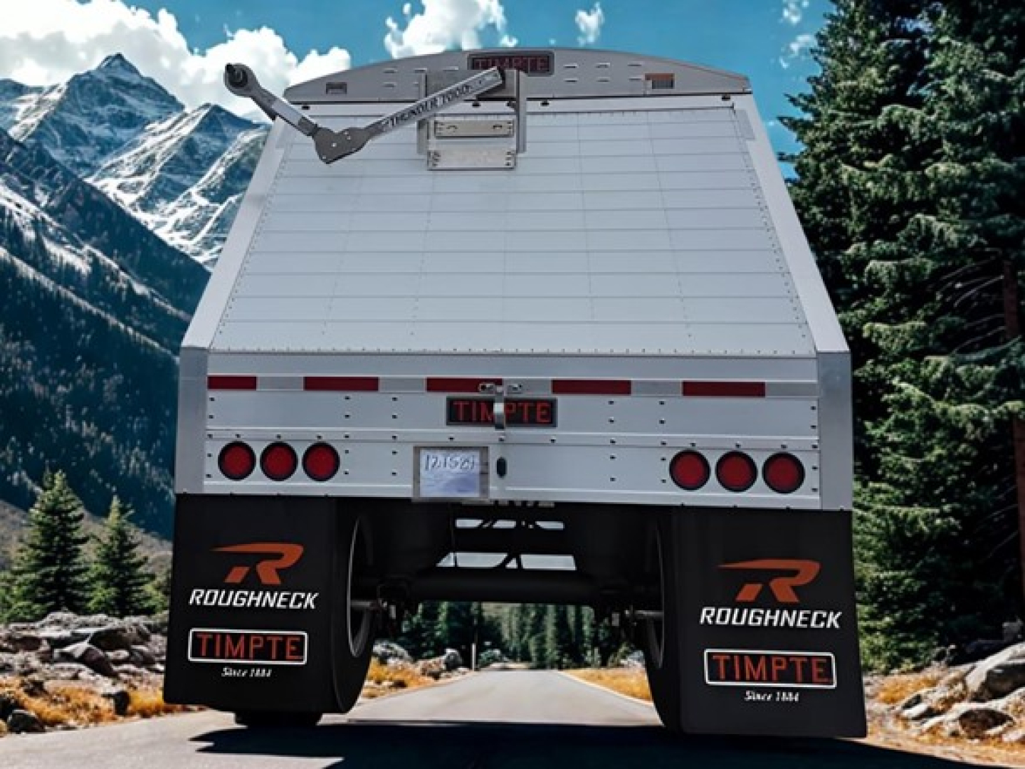 Timpte Super Hopper trailer rear view showing mud flaps with Roughneck and Timpte logos, mountain backdrop.