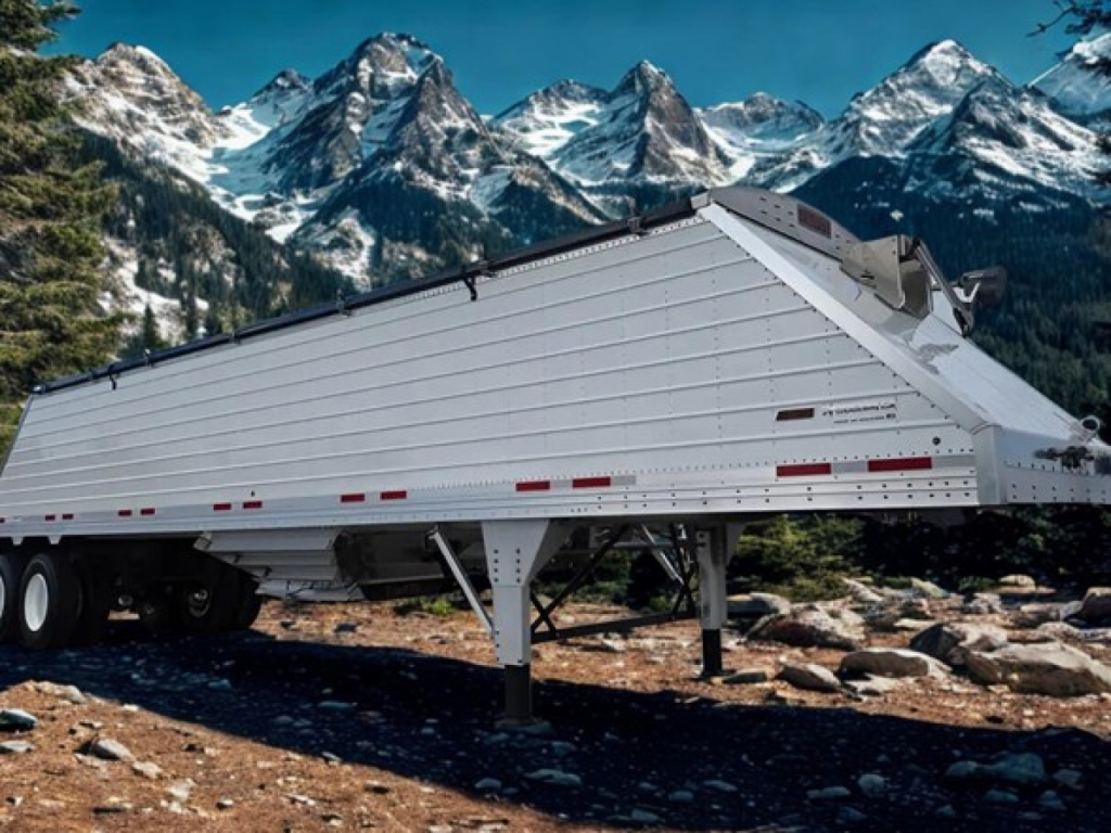 Trailer showing a 2026 Timpte Super Hopper with aluminum side panels and carrier, resting on landing gear with a mountainous backdrop.