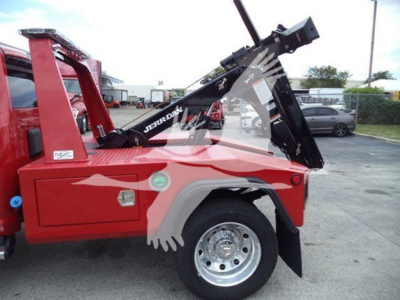 Ram 4500 SLT winch truck body side view with black tow crane arm and chrome wheel; red exterior with hydraulic winch apparatus partially raised