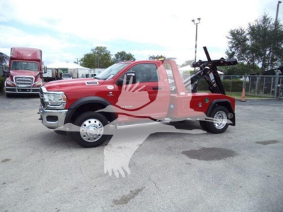 Ram 4500 tow truck in red with winch, side view showing chrome front bumper, dual rear wheels, and hoist equipment in truck bed.