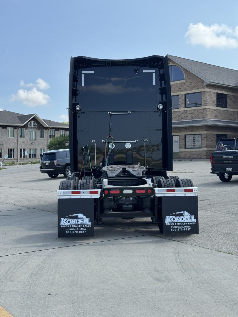 Peterbilt 579 tractor rear view showing fifth wheel, mud flaps with Kordell branding, and chassis with spare tires and air lines.