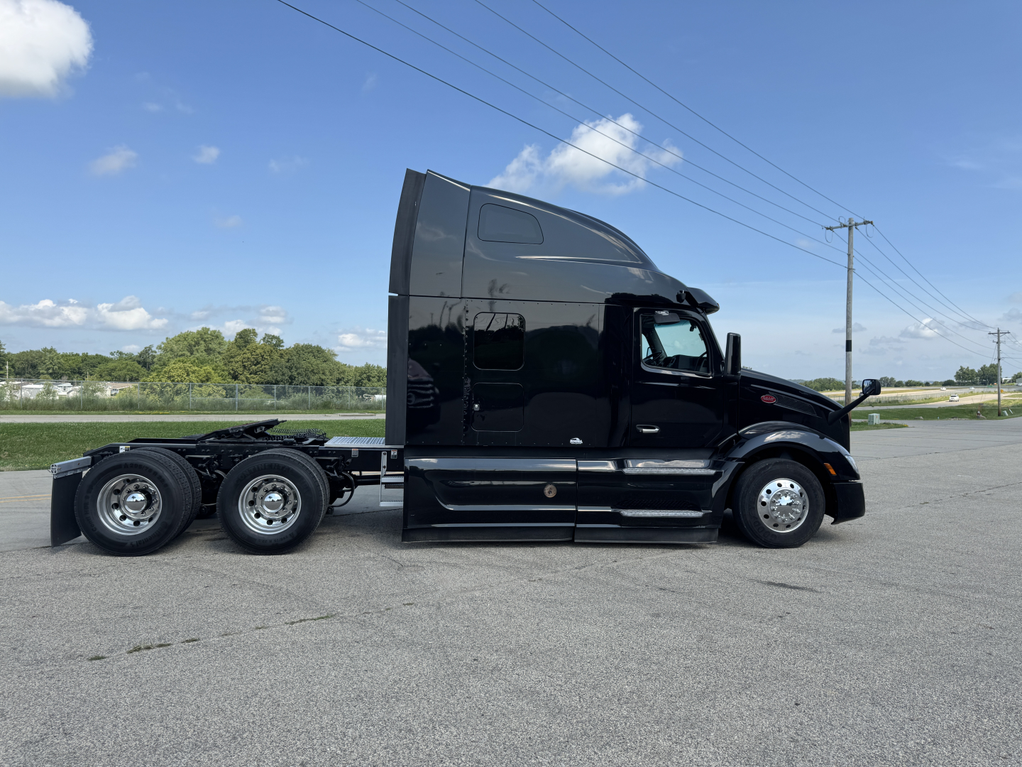 Peterbilt 579 conventional sleeper truck side view showing triple rear axles and black glossy finish with tall aerodynamic sleeper cab.