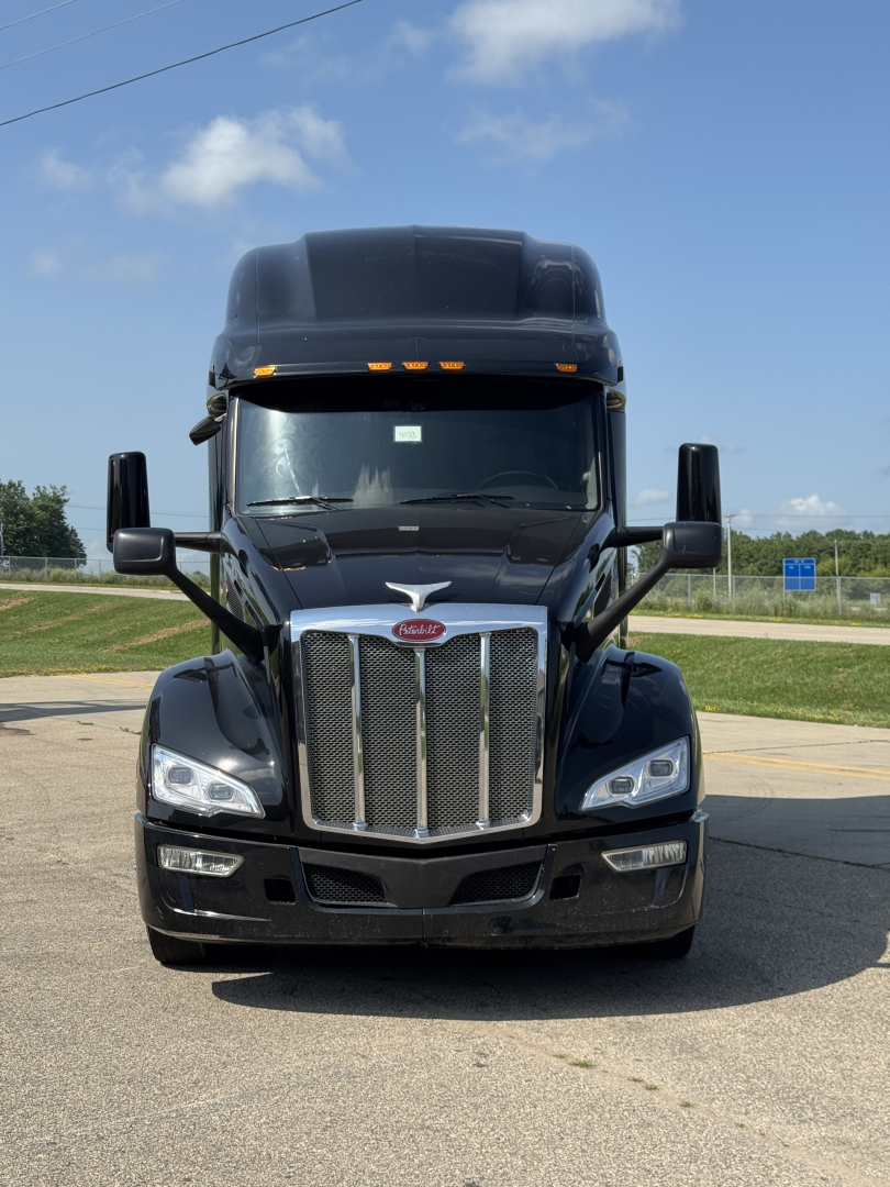 Peterbilt 579 class-8 truck front view showing chrome grille, headlights, and black hood; cab roof air fairing visible.