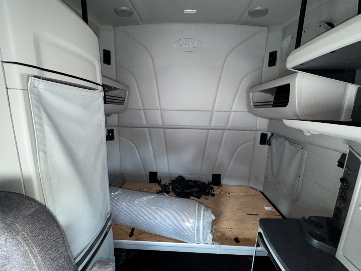 Peterbilt 579 sleeper cab interior showing cargo area with wooden floor and storage compartments, dash area visible, no text readable.