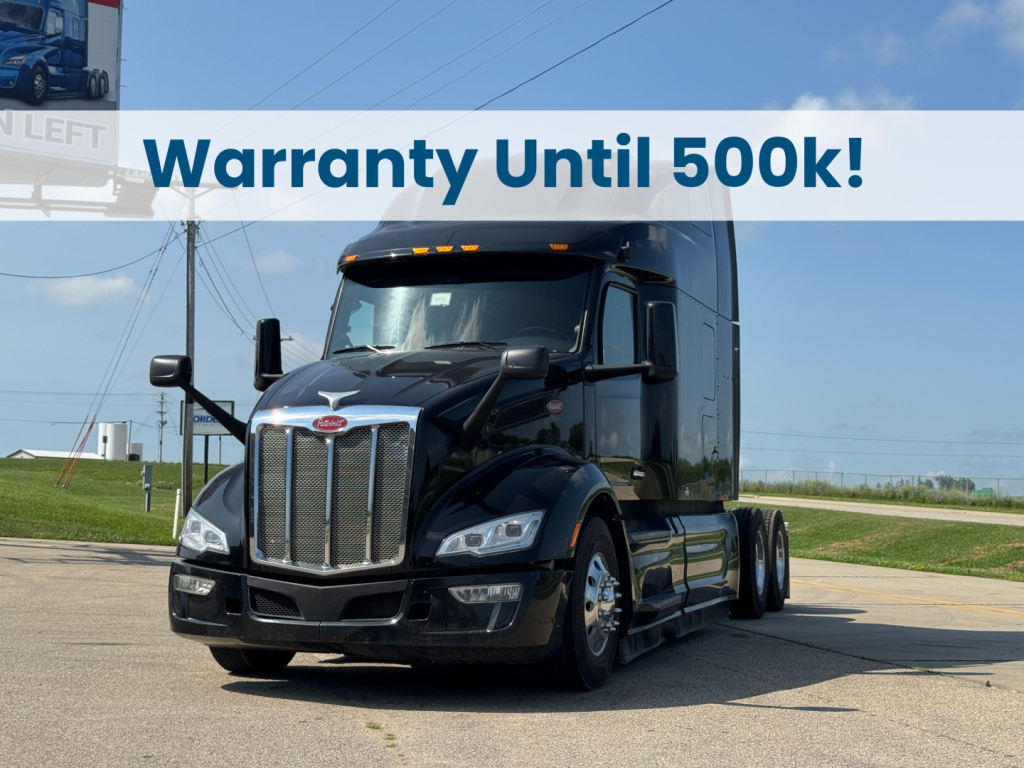 Peterbilt 579 conventional sleeper truck in a dealership lot with a banner reading Warranty Until 500k!