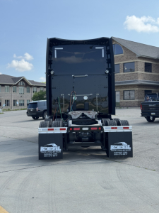 Peterbilt 579 tractor rear view showing fifth wheel, mud flaps with Kordell branding, and chassis with spare tires and air lines.