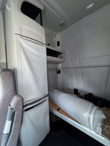 Peterbilt 579 sleeper cab interior showing storage cabinet and folded bunk mattress with windowed pocket, light gray interior