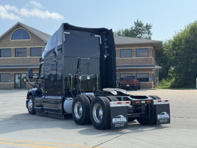Peterbilt 579 tractor rear view showing sleeper cab, dual rear axles, and hitch area with mud flaps and fuel tanks visible.