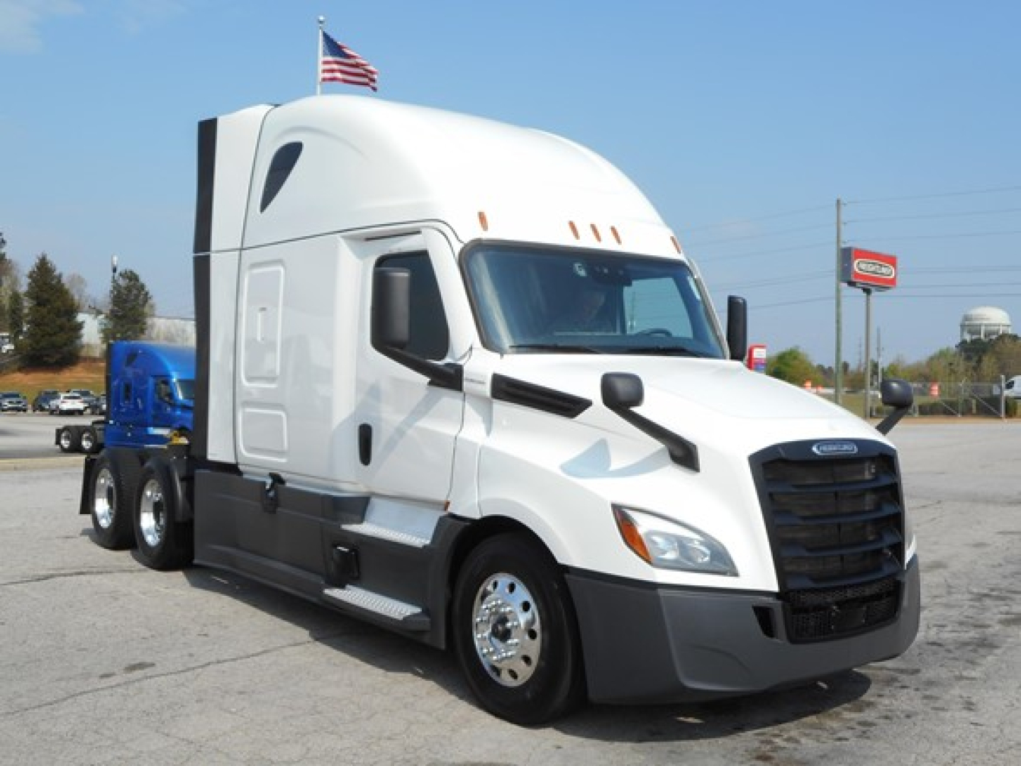 Truck engine bay showing Freightliner Cascadia 126 tractor with sleeper cab and fuel tanks.