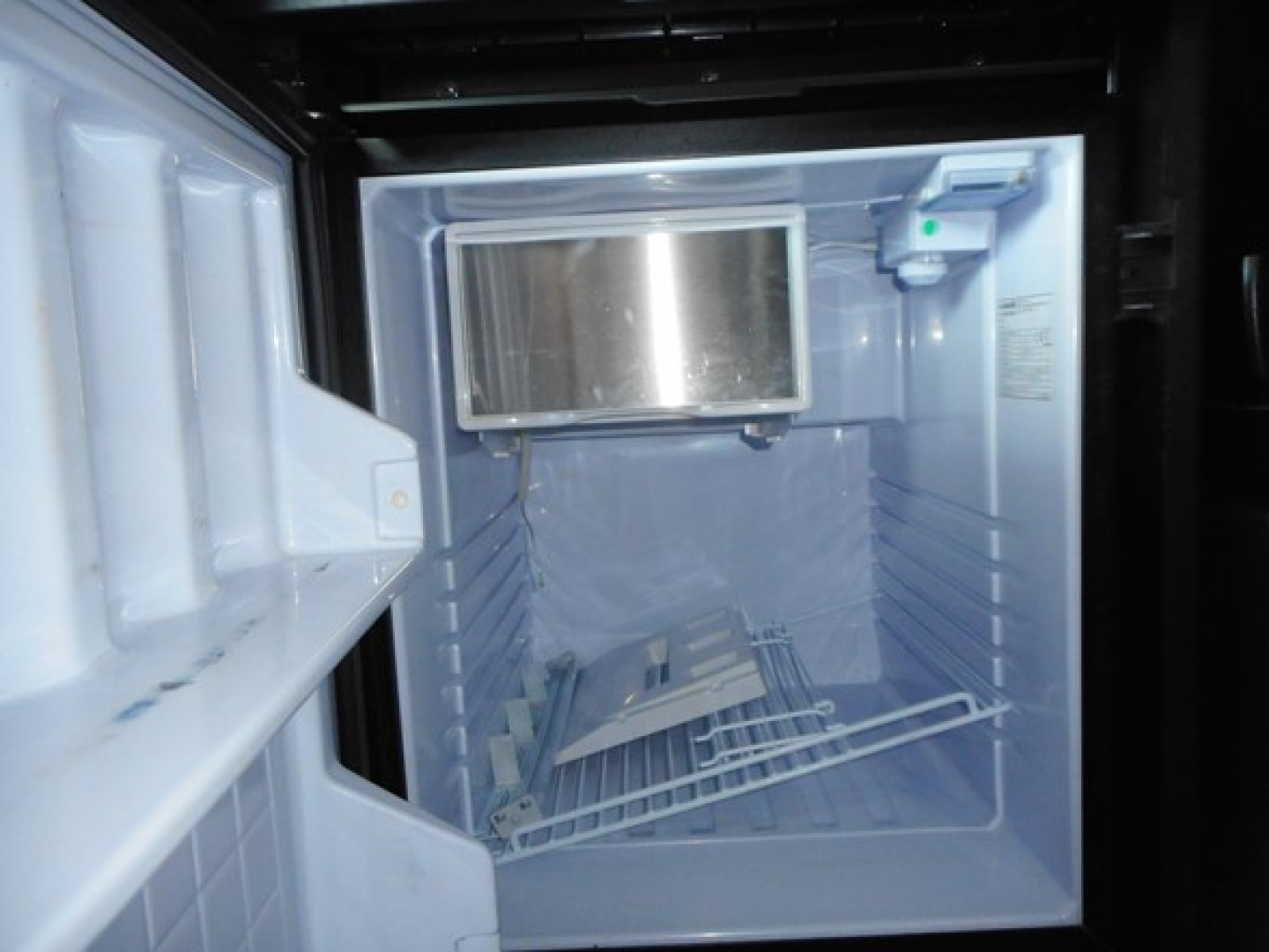 Fridge/freezer unit in a truck cab showing open door and empty shelves.