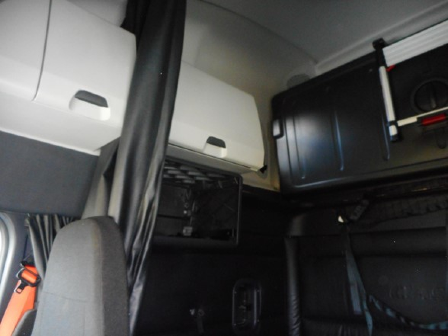 Cab interior of a Freightliner truck showing storage compartments and a seat with belt. Visible text includes part of the sleeper area and shelves.