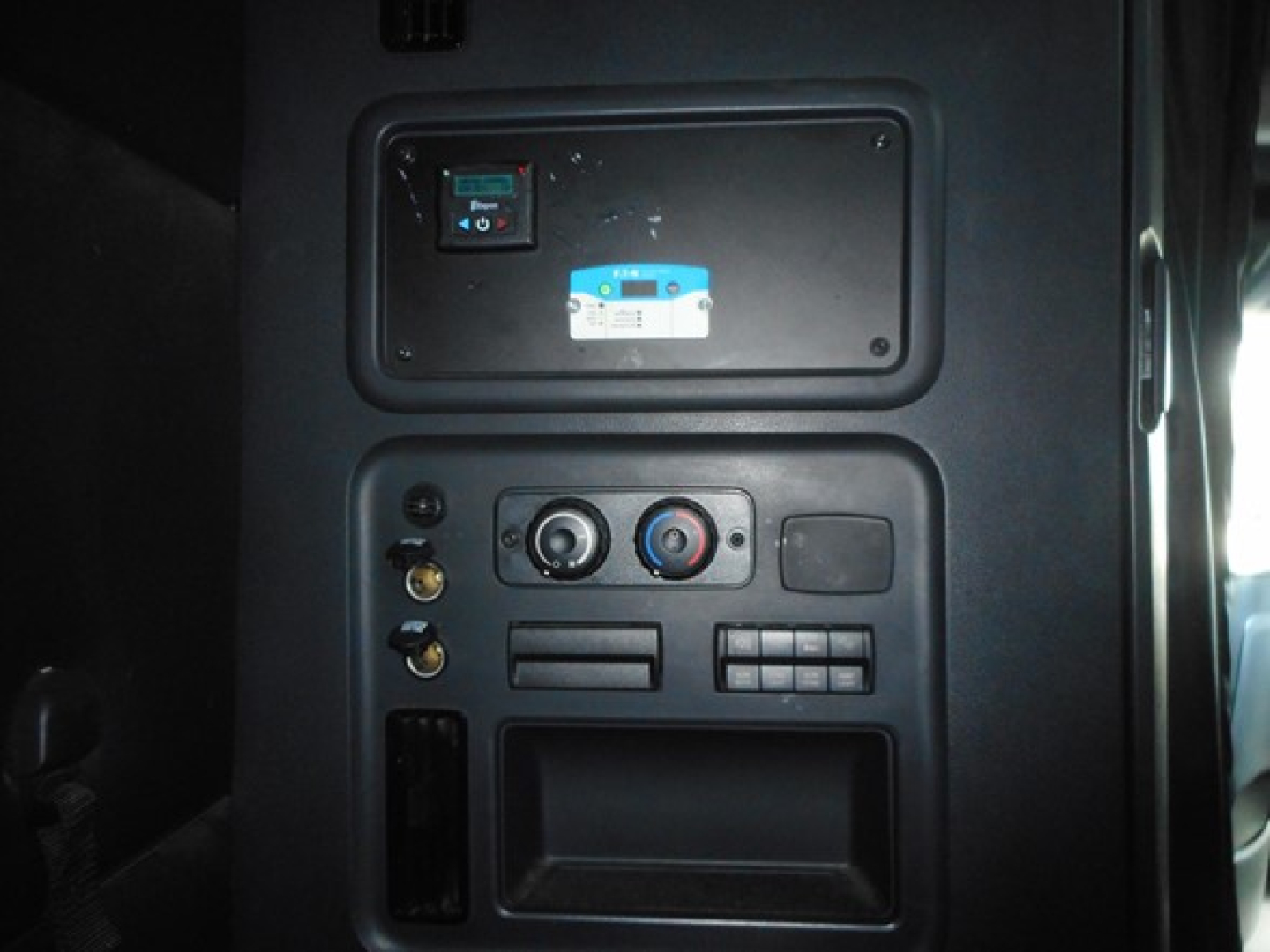 Panel with control switches and vents in Freightliner Cascadia sleeper cab showing a small switch panel and circular knobs.