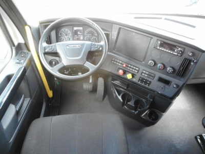 Cab interior of a Freightliner Cascadia 126 truck showing steering wheel, dashboard with gauges, center console, and cup holders.