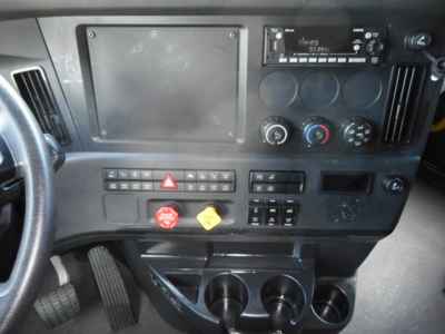 Freightliner Cascadia dash and controls showing radio, dashboard switches, and cup holders.
