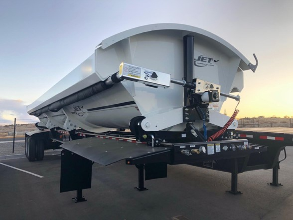 Jet air ride side dump trailer showing hydraulic lift, drop-down hopper and support legs with Jet branding and safety decals.