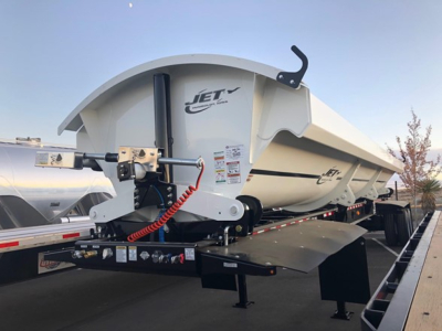Jet Air Ride Side Dump trailer showing hydraulic system and white hopper with Jet logo, mounted on a flatbed trailer.