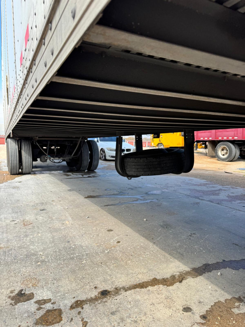 Trailer underside view showing suspension and landing gear of a used 2003 Wabash TL trailer, rear wheels visible with asphalt ground beneath.