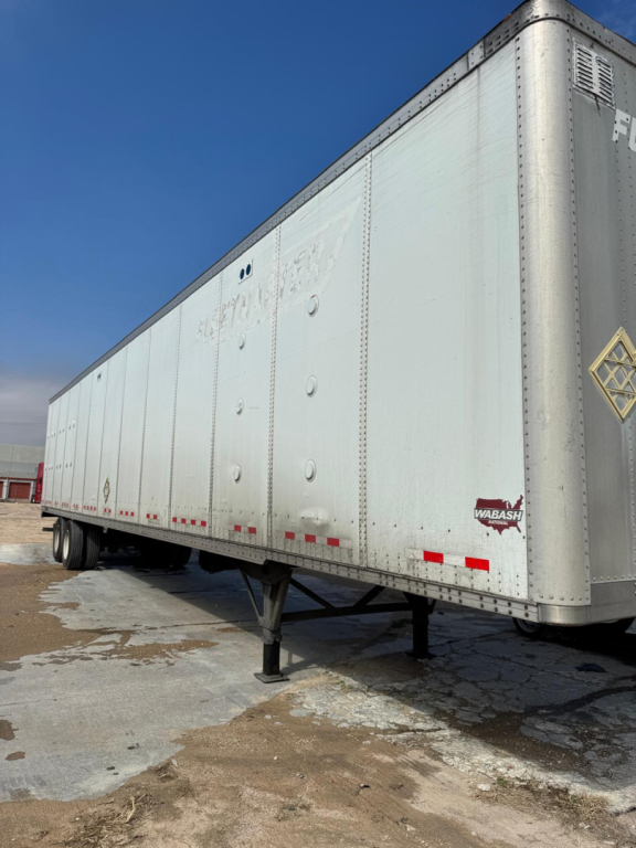 Trailer side view showing Wabash logo and support legs with blue sky.