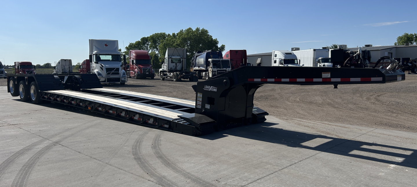 Lowboy trailer with long flatbed and ramp sections. Side shows Load King 503/554 SS SF branding on the gooseneck. 18' wheelbase and 8'-6" deck length visible.