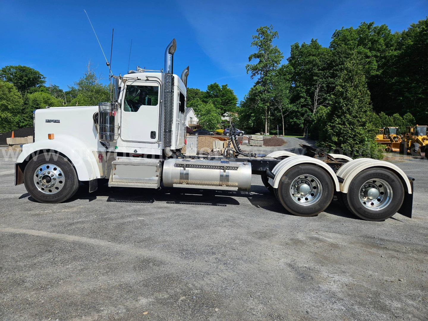 Kenworth W900L tractor unit side view showing chrome fuel tanks and wheels, no specific legible text visible on image.