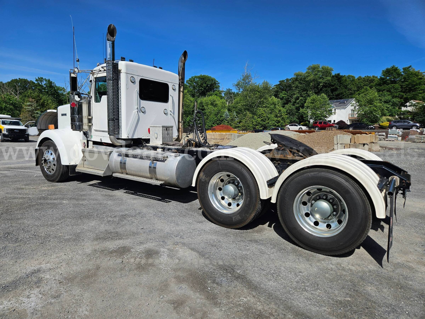 Kenworth W900L tractor shown in side view with dual rear axles and chrome fuel tanks.
