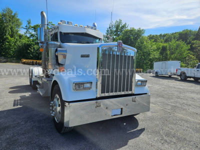 Kenworth W900L heavy duty truck front view showing large chrome grille and bumper with chrome exhaust stacks.