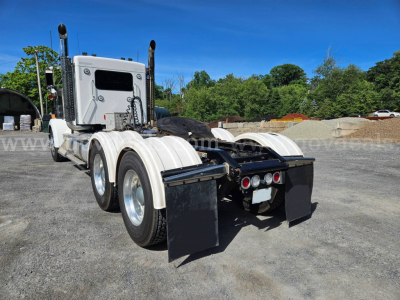 Kenworth W900L truck tractor rear view showing dual rear axles and mud flaps with deck plate
