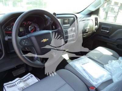 Chevrolet Silverado 6500HD cockpit interior showing steering wheel with Chevy emblem, dashboard, center console, and front passenger seat with plastic covering.