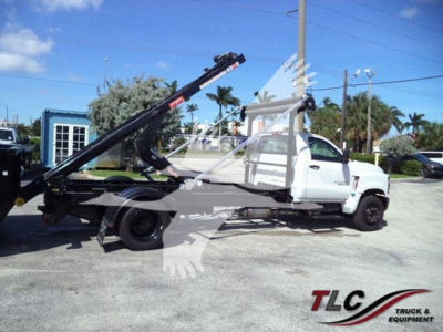 Chevrolet Silverado 6500HD roll-off truck side view showing hydraulic boom and crane system with white cab and gray chassis.