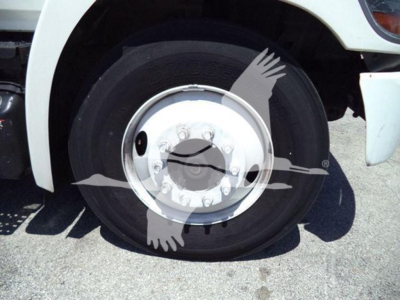 Truck wheel close-up showing front tire and chrome hubcap on the Hino 268a series refrigerated truck.