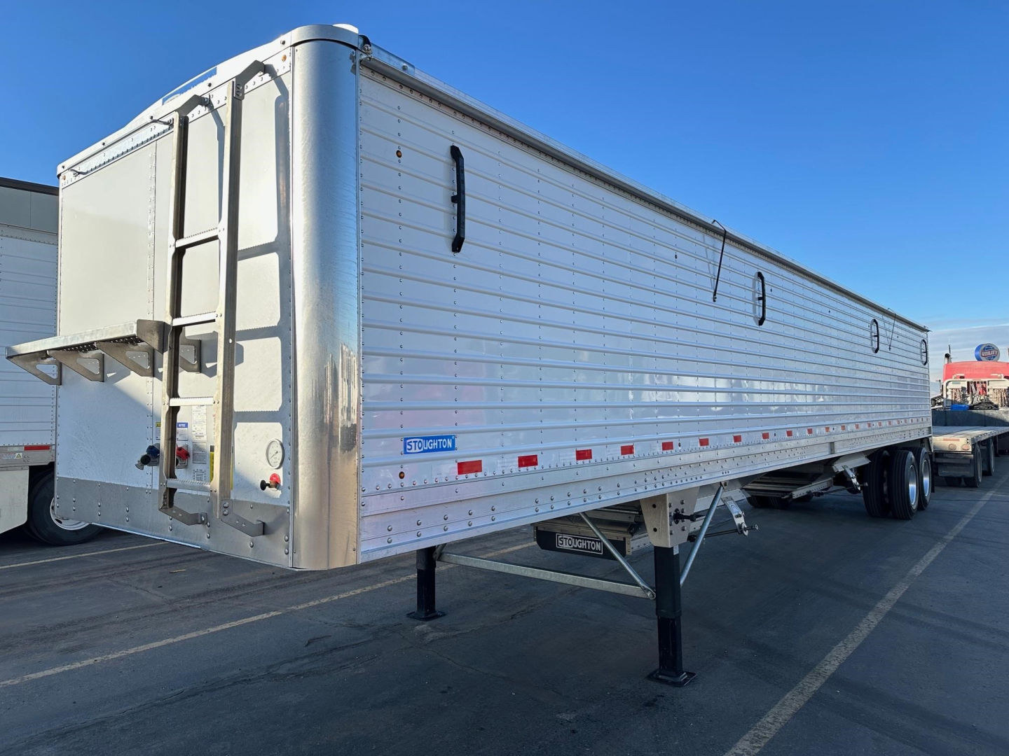Stoughton grain trailer with air ride hopper and 74-inch sides, aluminum body, rear and side access doors, trailer standing on landing gear.