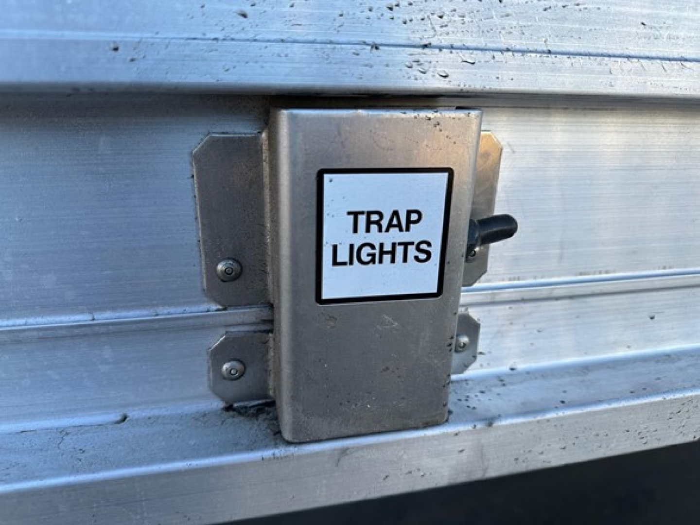 Trailer showing a metal access box labeled Trap Lights mounted on the side of a Stoughton grain trailer.