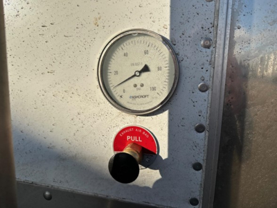 Stoughton grain trailer gauge panel showing pressure gauge and red 'PULL' handle near a black knob.