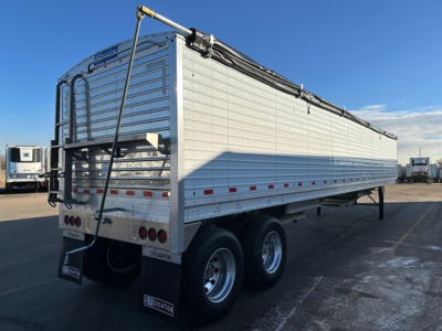 Stoughton grain trailer rear and side view showing hopper trailer with silver aluminum panels and dual rear wheels.